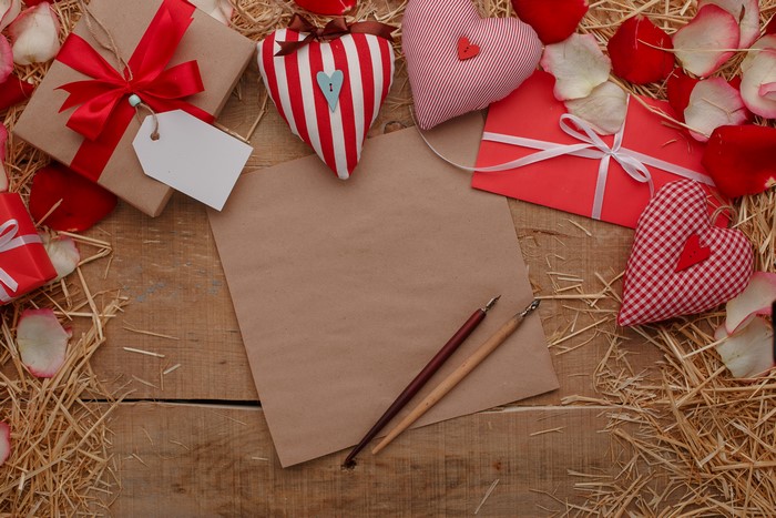 Valentine's Day gift box, hearts, and writing tools on wood