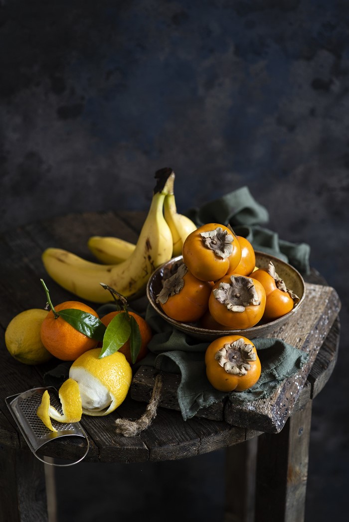 Still life of bananas, lemons, tangerines, and persimmons