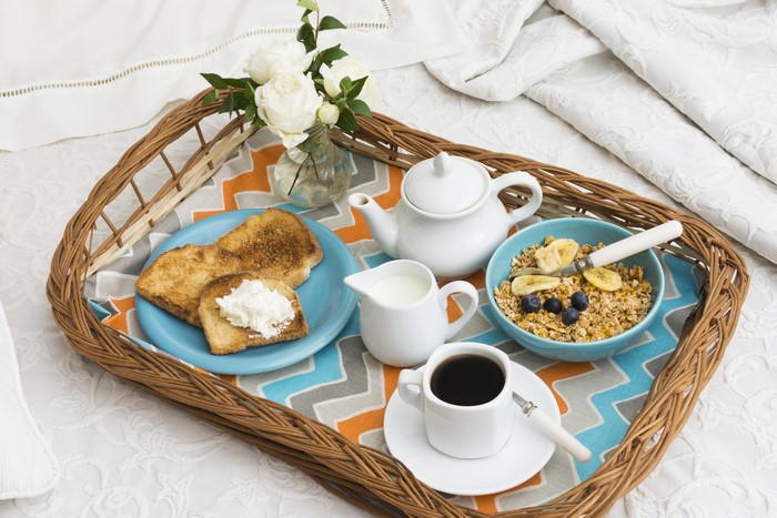 Breakfast tray with muesli, toast, coffee, and roses