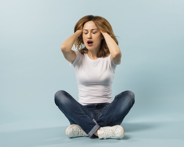 Woman sitting with hands on head