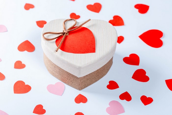 Heart-shaped gift box surrounded by paper hearts