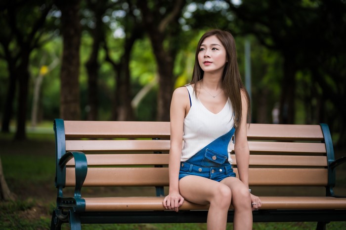 Asian woman sitting on a park bench