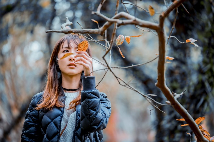 Asian woman holding a leaf in front of her face