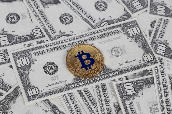 Bitcoin coin on US 100 dollar bills
