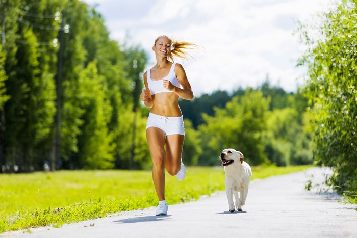 Woman running with a dog on a trail