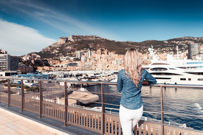 Woman in denim shirt looking at Monaco harbor with yachts