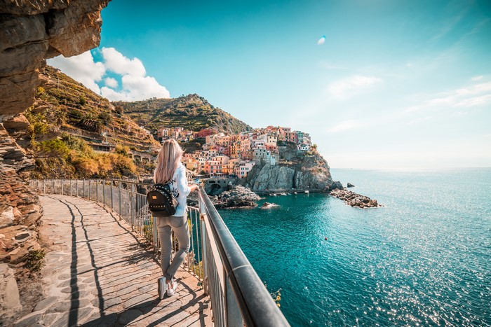 Blonde girl with backpack in Manarola, Italy