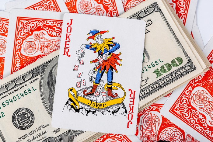 Joker playing card on US dollar bills and red playing cards