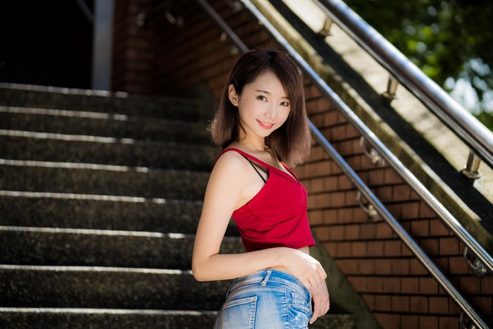 Asian woman in red top and jeans on stairs