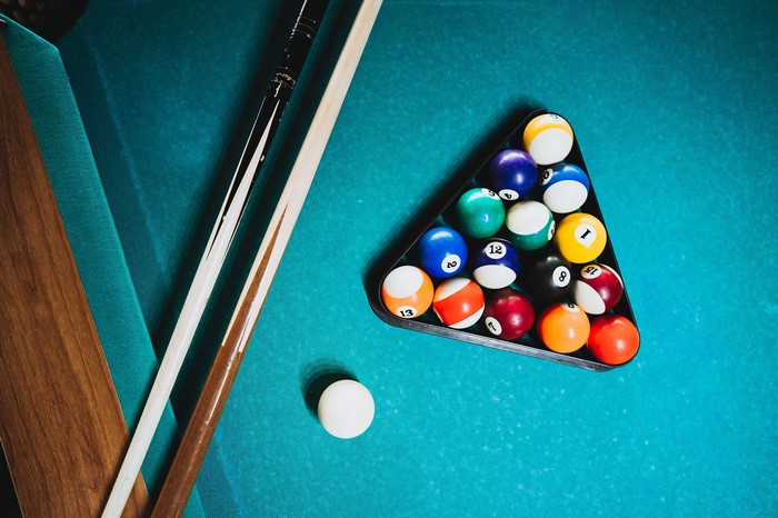 Billiard balls racked on a pool table with cues