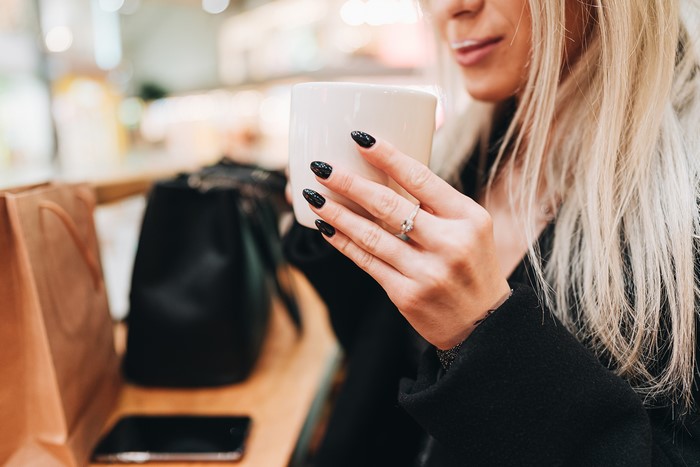 Woman with black manicure holding a mug