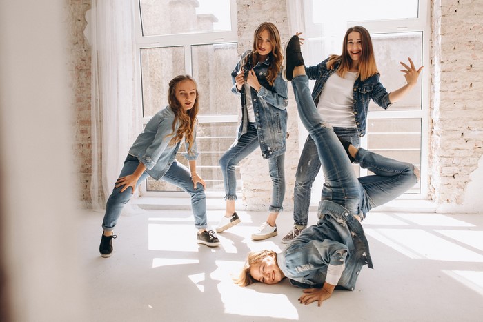 Four young women in denim outfits dancing