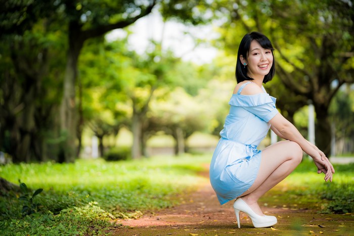 Asian woman in blue dress posing in park