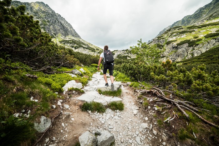 Man with backpack hiking on a rocky mountain trail