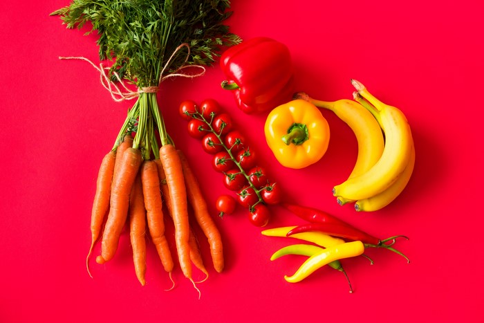 Carrots, Tomatoes, Bell Peppers, Chili Peppers, and Bananas on Red Background