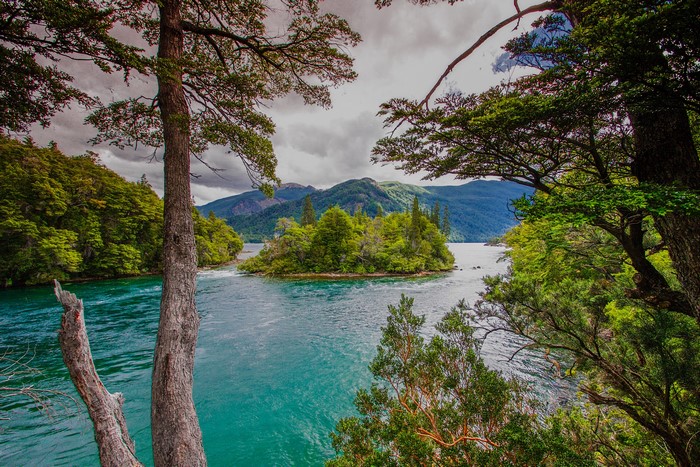 Island in a turquoise bay surrounded by trees and mountains in Patagonia, Argentina