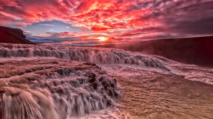 Waterfall at sunset with dramatic red clouds