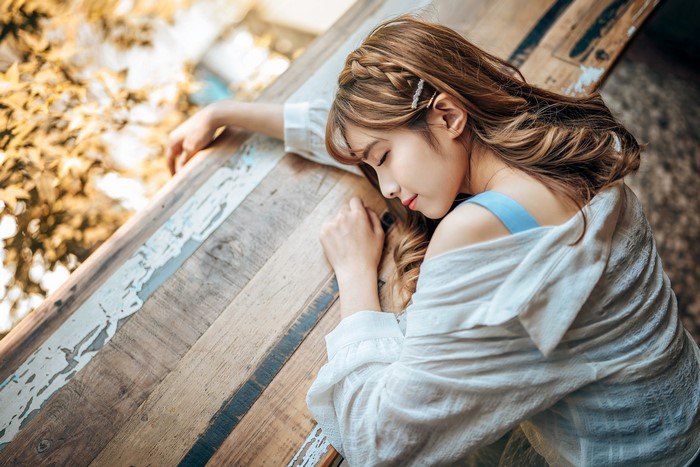 Asian woman with brown hair sleeping on a wooden surface