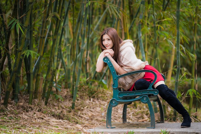 Asian woman sitting on a bench in a bamboo forest