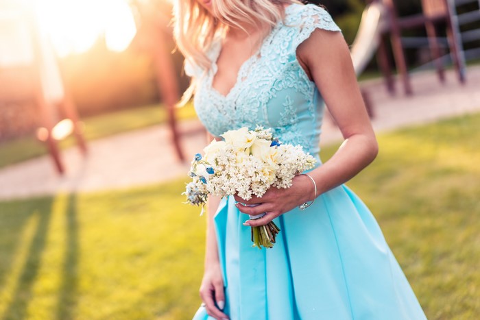 Blonde girl in a blue dress holding a bouquet