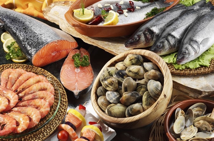 Assortment of fresh seafood including salmon, sea bass, shrimp, and clams