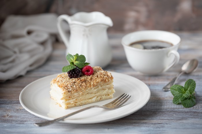 Slice of Napoleon cake with berries and coffee