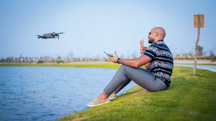 Man controlling a drone by a lake