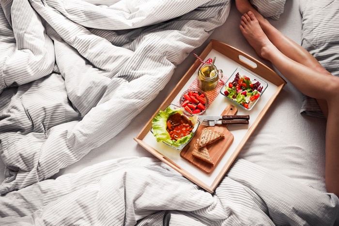 Breakfast tray with salad, strawberries, and toast in bed with legs