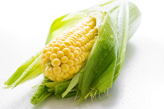 Corn with water drops and green leaves