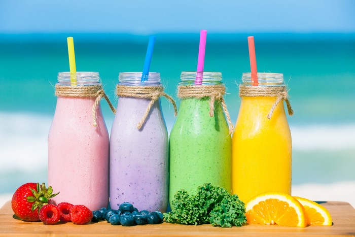 Four Smoothies with Fruits on Beach Background