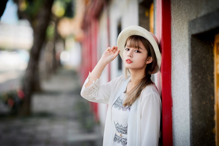 Asian woman wearing a hat and white cardigan