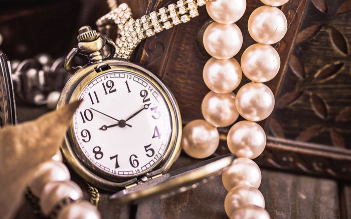 Pocket watch and pearls on a wooden surface