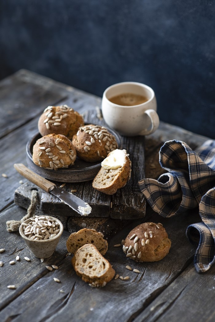 Coffee and sunflower seed buns on wooden table