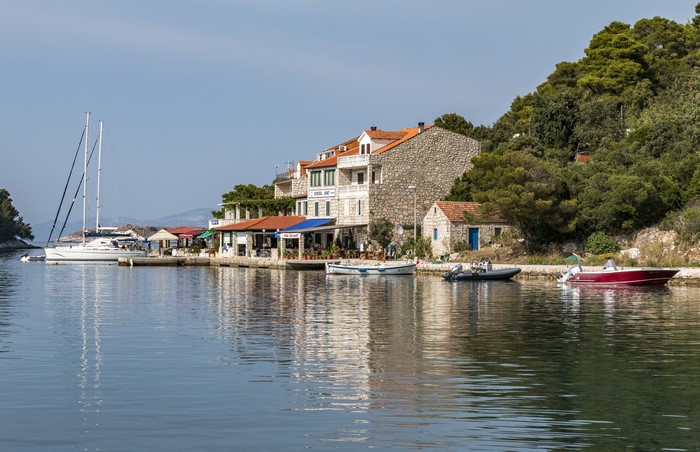 Boats docked in a harbor with buildings and trees in Pomena, Mljet, Croatia