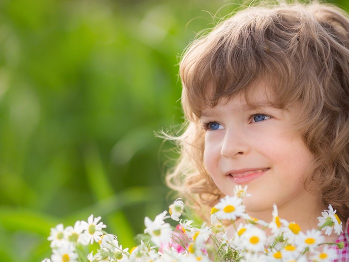 Young girl with blue eyes and blonde hair holding daisies