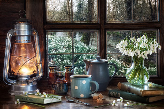 Still-life with snowdrops, kerosene lamp, and coffee set by the window