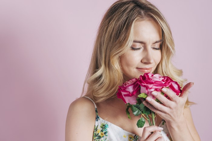 Blonde girl smelling pink roses