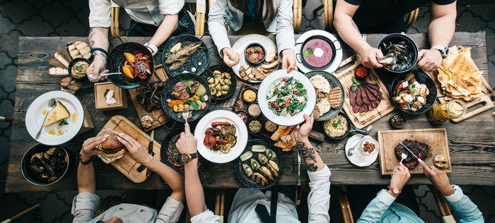 Many people eating at a table with many dishes