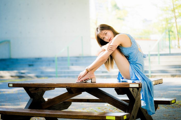 Asian woman in blue dress sitting on table
