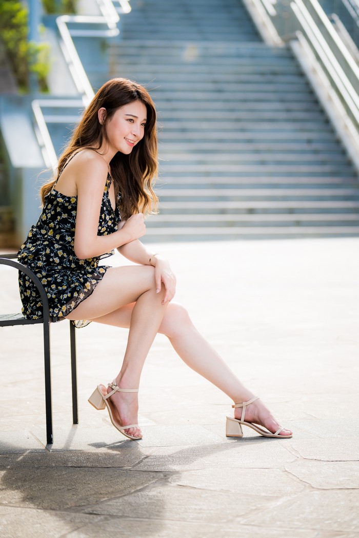 Asian Woman Sitting on Bench in Floral Dress