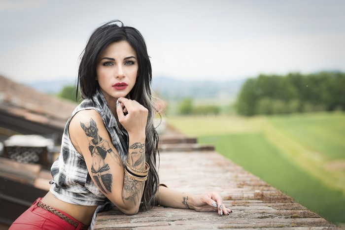 Woman with tattoos leaning on a wall