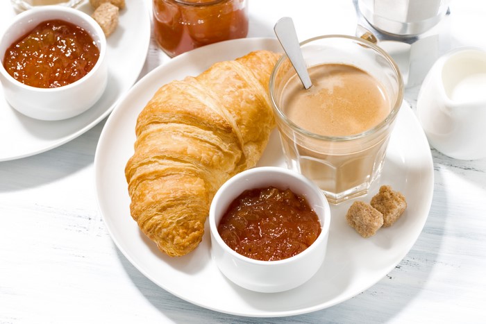 Croissant with jam and coffee on a plate