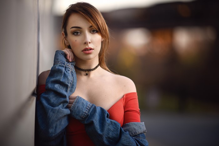 Woman with brown hair wearing a red top and denim jacket