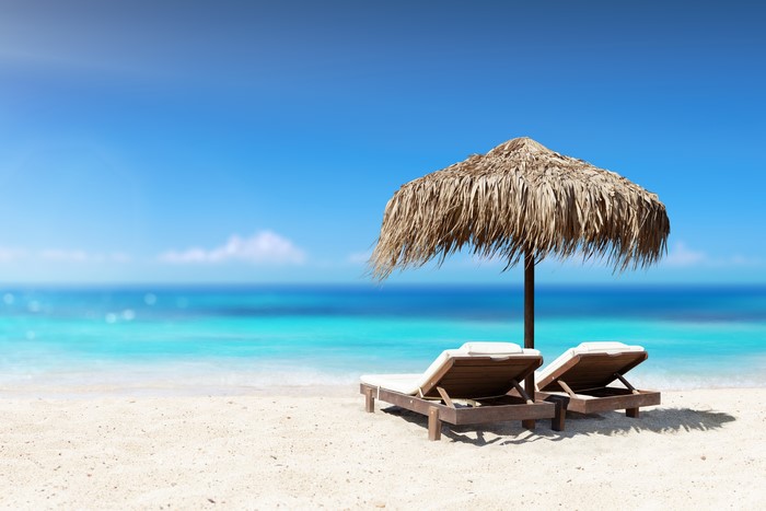 Beach with two sunloungers and a thatched umbrella