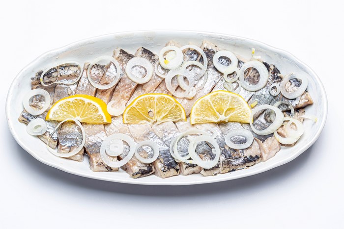 Sliced Herring with Onion and Lemon on a Plate