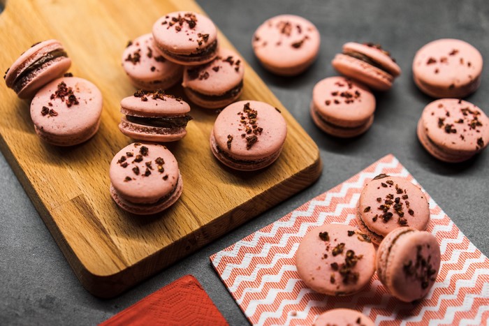 Pink macarons with chocolate filling on a cutting board