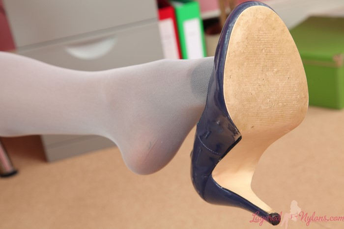 Closeup of a foot in white pantyhose wearing a blue stiletto heel