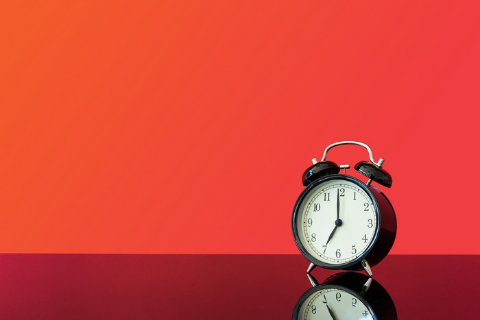 Alarm clock on a red background with reflection