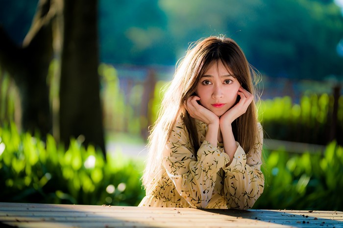 Asian woman with brown hair resting chin on hands