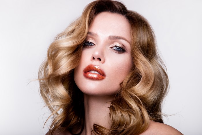 Woman with blonde wavy hair and dramatic makeup